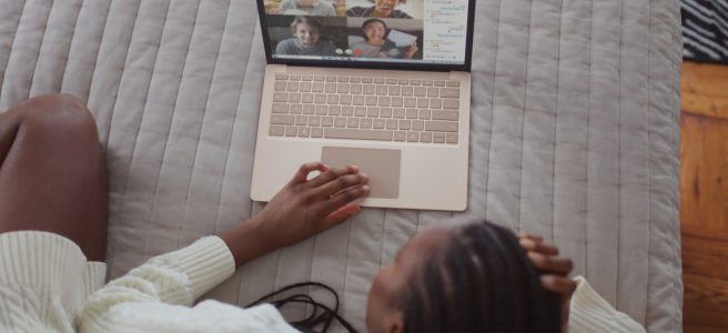 Person sitting on their bed, having a video conference on their laptop
